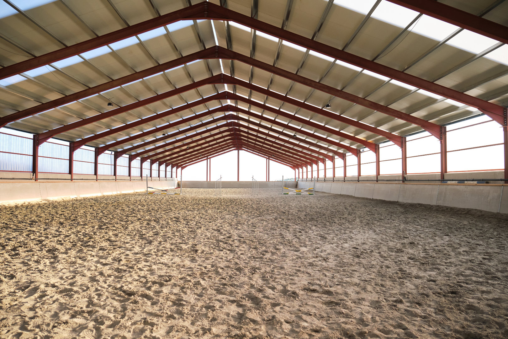 Hall d'équitation vide avec des barrières de saut.